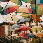 Image of multi-color umbrellas hanging from lines between buildings