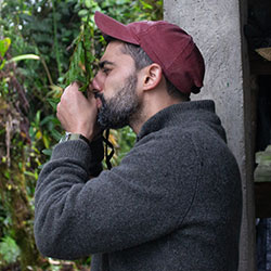 Man in red cap in a forest pressing face to leaf